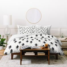 a bed with black and white palm trees on the comforter is shown in front of a round mirror