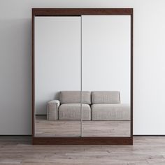 a couch sitting in front of a mirror on top of a wooden floor next to a white wall