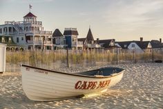 a small boat sitting on top of a sandy beach next to a tall white building