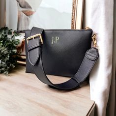 a black purse sitting on top of a wooden table next to a framed photo and potted plant