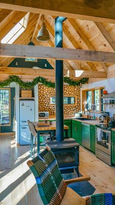 an open kitchen and living room area with wood flooring, green cabinets and stove top oven