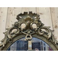 an ornate gold mirror on a wooden wall