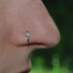 a woman's nose with a small blue stone in the middle of her nose