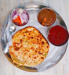 a silver plate topped with food next to sauces and condiments on a table