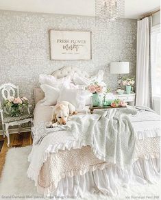 a dog laying on top of a white bed in a bedroom next to a window