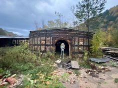 an abandoned train station in the woods with trees and rocks around it's entrance