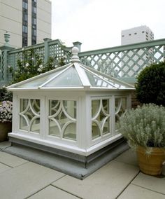 a white gazebo sitting on top of a patio next to potted planters