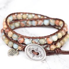 Genuine leather and beautiful Jasper stones that will remind you of a sunny beach, make up this gorgeous double wrap bracelet. Sand, dreamy light blue, and hints of rust swirl around in these stones and contrast nicely against a bold brown leather. 6mm (.62") diameter Aqua Terra Jasper gemstones Oval silver button, about 19mm (3/4") in width Rust brown leather Signature Bluefish logo heart charm 34 - 39 cm/13.5 - 15.5" length 2 button loop adjustments to fit most wrists Logo Heart, Beaded Leather Wraps, Aqua Terra, Double Wrap Bracelet, Silver Button, Sunny Beach, Silver Buttons, Bead Leather, Jasper Stone