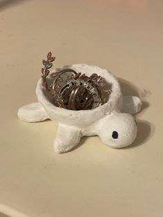 a white turtle figurine with several watches in it's shell