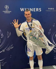 a man holding a silver trophy in front of a blue wall with the words winners written on it