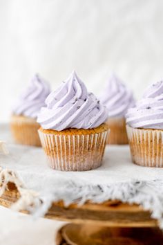 three cupcakes with white frosting sitting on top of a cake plate,