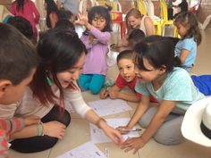 a group of children sitting on the floor looking at papers with scissors in their hands