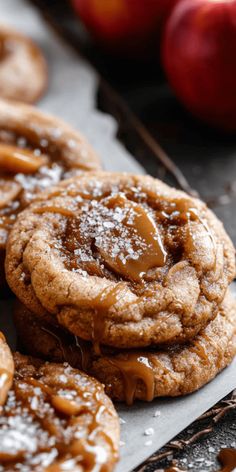 some cookies with caramel on them and apples in the background