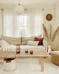 a living room filled with furniture and pillows on top of a table in front of a window