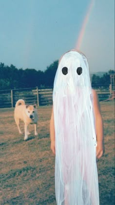 a child in a ghost costume standing next to a dog