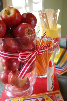 there are many apples in the glass vases on the table with candy canes