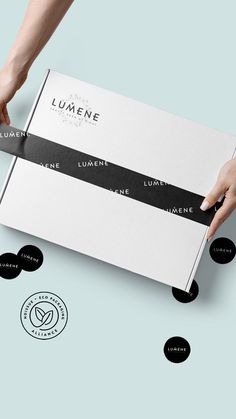 a person holding a box with black and white labels on it that read lumene