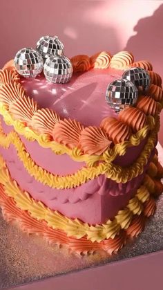 a heart shaped cake with two disco balls on it's top and some decorations around the edges