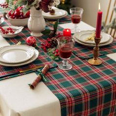 the table is set for christmas dinner with red candles