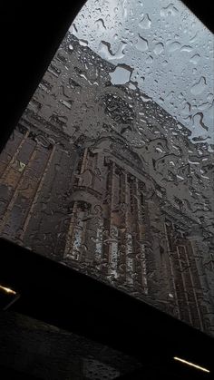 rain is falling on the windows in front of an old building with a clock tower