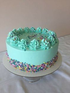 a cake with blue frosting and sprinkles on a white tablecloth