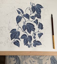 a piece of paper with blue leaves on it next to a pencil and drawing supplies