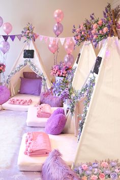 a room filled with lots of purple and pink decorations on top of white sheets covered in balloons