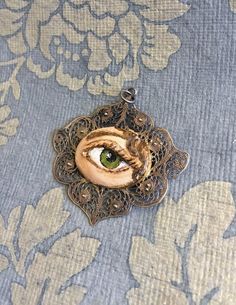 "Hand-painted Lover's Eye vintage silver filigree pendant. This piece of jewelry is a one of a kind, hand-painted by me on a vintage piece of jewelry selected also by me. It's painted with acrylic paint and varnished for protection and signed on the inside of the pin. The pendant is 1 3/4 wide x 1 1/2 inch wide. It comes with a silver plated chain - 18 inches long. \"The lover's eye is an 18th century variation on a portrait miniature of a secret love which typically displayed only the eye and e Vintage Hand Painted Round Pendant Necklace, Vintage Hand Painted Pendant Jewelry, Vintage Hand Painted Necklace As Gift, Vintage Hand Painted Necklaces For Gift, Hand Painted Vintage Necklace As Gift, Hand Painted Vintage Necklace For Gift, Vintage Hand-painted Pendant Necklace, Vintage Hand Painted Pendant Necklace, Vintage Enamel Jewelry Handmade