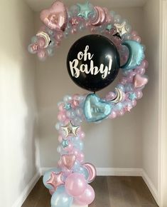 a balloon arch that says oh baby surrounded by balloons in pastel blue, pink and white colors