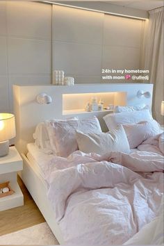 a bed with white comforter and pillows in a bedroom next to a night stand