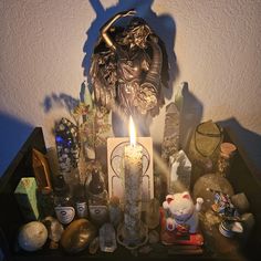 a candle is lit in front of an angel statue and various other items on a shelf