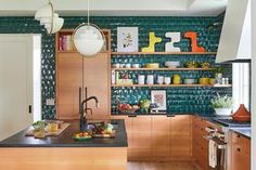 a kitchen with wooden cabinets and black counter tops in front of a green tiled wall