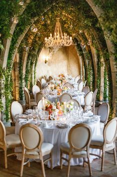 an outdoor dining area with tables, chairs and chandeliers set up for a formal function