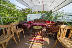 an outdoor area with chairs, tables and rugs on the floor under a white awning