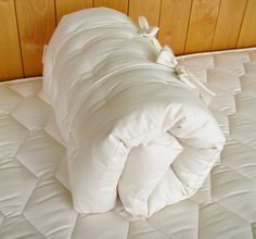 an unmade bed with white sheets and pillows on it's bottom edge, against a wood paneled wall