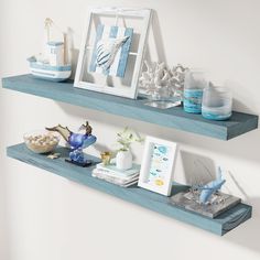 two blue shelves with pictures, seashells and other items on them against a white wall