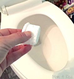 a hand holding a piece of toilet paper in front of a toilet