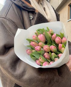 a woman holding a bouquet of pink tulips