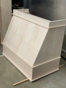 a white wooden box sitting on top of a floor next to a pile of wood