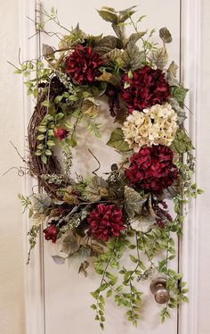 a wreath with red and white flowers hanging on a door