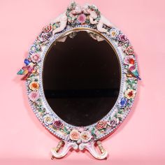 the mirror is decorated with colorful flowers and cherubs on it's sides