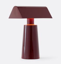 a red table lamp sitting on top of a white floor