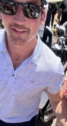 a man wearing sunglasses and a hat poses for a photo with a woman in front of motorcycles