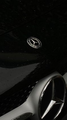 the front end of a car that is black and silver with an emblem on it