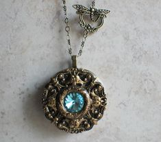 "Turquoise rivoli crystal music box pendant. This round music box pendant is inspired by the gorgeous music box pendants of era's gone by. Music box is pill box size, please look at the dimensions for exact size. A perfect round bronze locket has been adorned with layers of bronze filigree and Turquoise Rivoli Crystal in the center. The bronze filigree layers have been sealed in a clear resin to give a glass like finish and preserve the beauty of this musical pendant. The music box winds from a Talisman Jewelry Pendants, Music Box Necklace, Box Necklace, Music Box Jewelry, Turquoise Crystal, Magical Jewelry, Rose Jewelry, Necklace Box