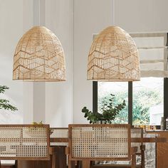 two lamps hanging from the ceiling above a dining room table with chairs and a potted plant