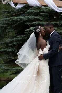 the bride and groom are kissing under an arch with white draping on it