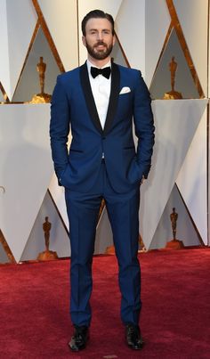 a man in a tuxedo and bow tie standing on the red carpet at an oscars event