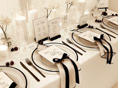 the table is set with black and white place settings, napkins, silverware, and candles