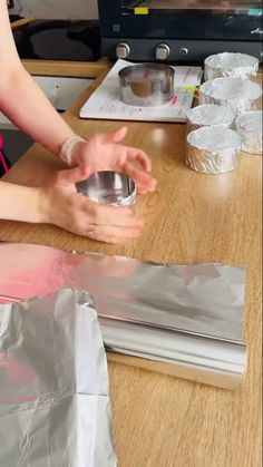 a woman sitting at a table with some tin foil around her and making something out of it